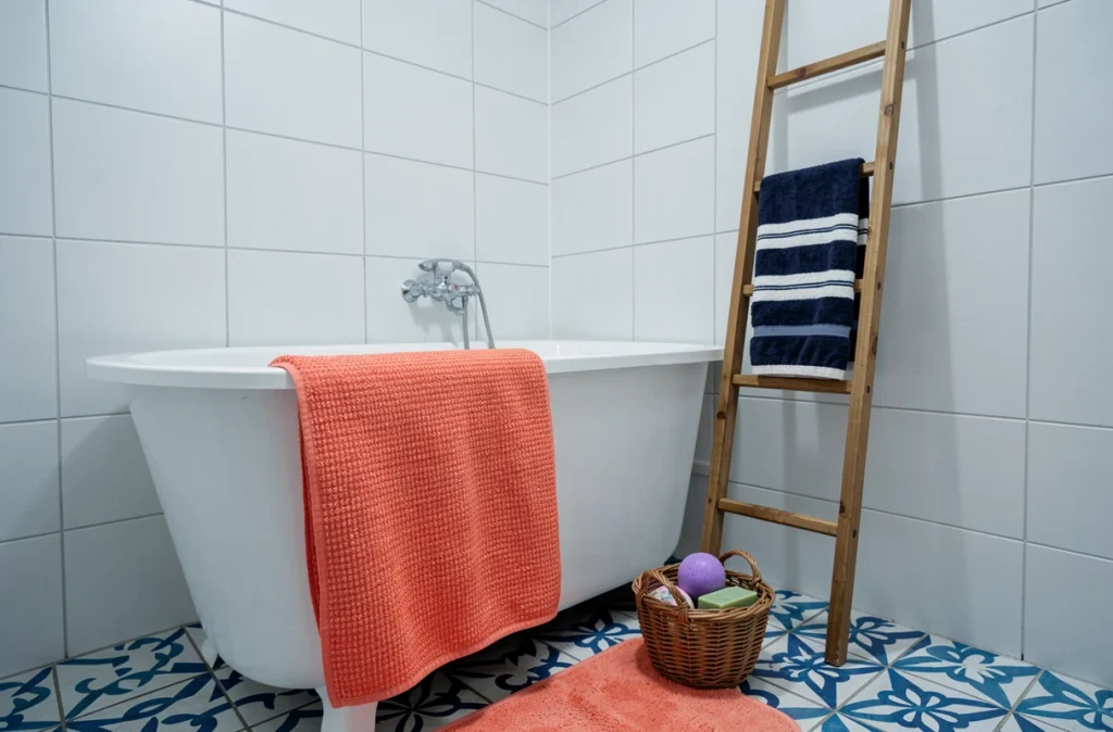Coin baignoire avec tapis coral, serviettes rayées marine et panier en rotin avec accessoires colorés